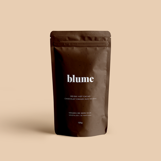 A sealed pouch of blume brand Reishi Hot Cacao Blend, with a dark brown color and the product name displayed prominently on the front.