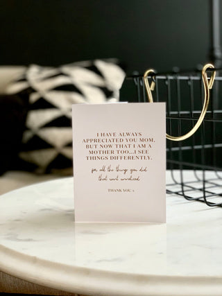 A greeting card with a quote embossed in gold foil on the front, accompanied by a white envelope.