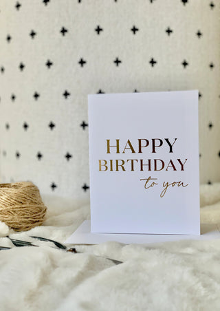 White card with 'Happy Birthday to you' text on a textured surface with twine and fabric.