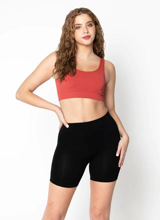 A woman wearing bamboo seamless shorts and a red cropped tank top. 