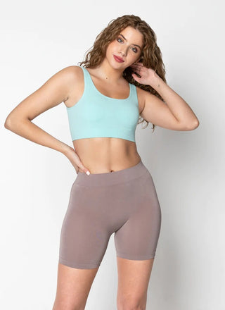 A woman wearing bamboo seamless shorts and a blue cropped tank top. 
