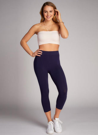 A person wearing  3/4 leggings and a white tube top. 
