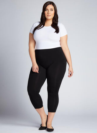 A model wearing black 3/4 length leggings and a white top.