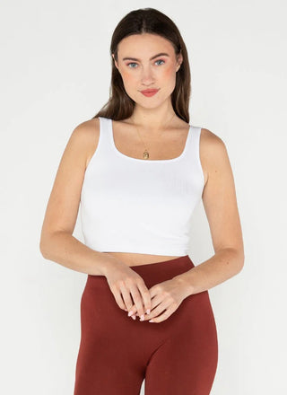 A woman wearing a square neck crop tank in a white color, with the tank displaying a ribbed texture.
