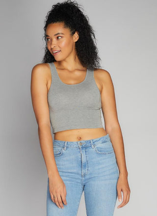 A woman wearing a grey bamboo cropped tank top paired with blue jeans. 