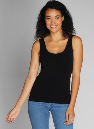 A woman wearing a black bamboo tank top with short length, paired with blue jeans.