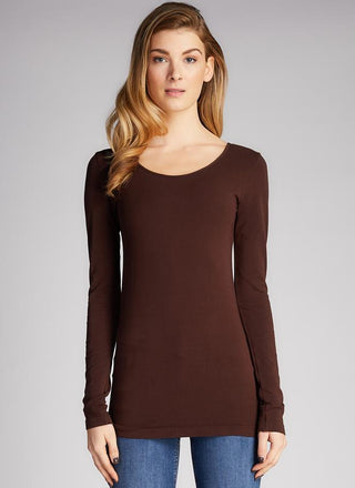 A woman wearing a long sleeve scoop neck top in brown, paired with blue jeans. 