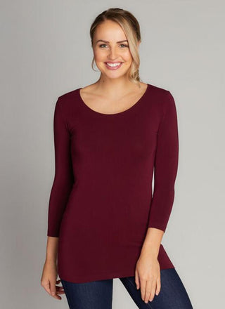 A woman wearing a red 3/4 sleeve scoop neck top made of bamboo, cotton, nylon, and spandex.