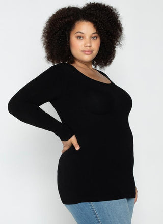 A woman wearing a black long sleeve curvy scoop neck top paired with blue jeans.