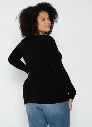 A woman wearing a black long sleeve curvy scoop neck top paired with blue jeans.