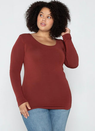 A woman wearing a brown long sleeve v-neck top paired with blue jeans.