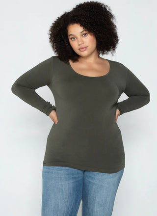 A woman wearing a olive long sleeve curvy scoop neck top paired with blue jeans.