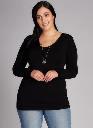A woman wearing a black long sleeve v-neck top paired with blue jeans.