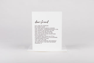 A greeting card with 'dear friend' written at the top, a message and a white envelope lying flat.