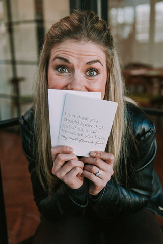 A woman holding a greeting card up to her face and smiling. 