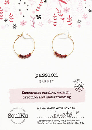 Garnet hoop earrings on a decorative card with floral patterns and text about the gemstone's properties.
