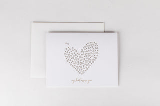 A greeting card with a gold foil embossed heart design and the text 'I miss you' on it, accompanied by a white envelope.